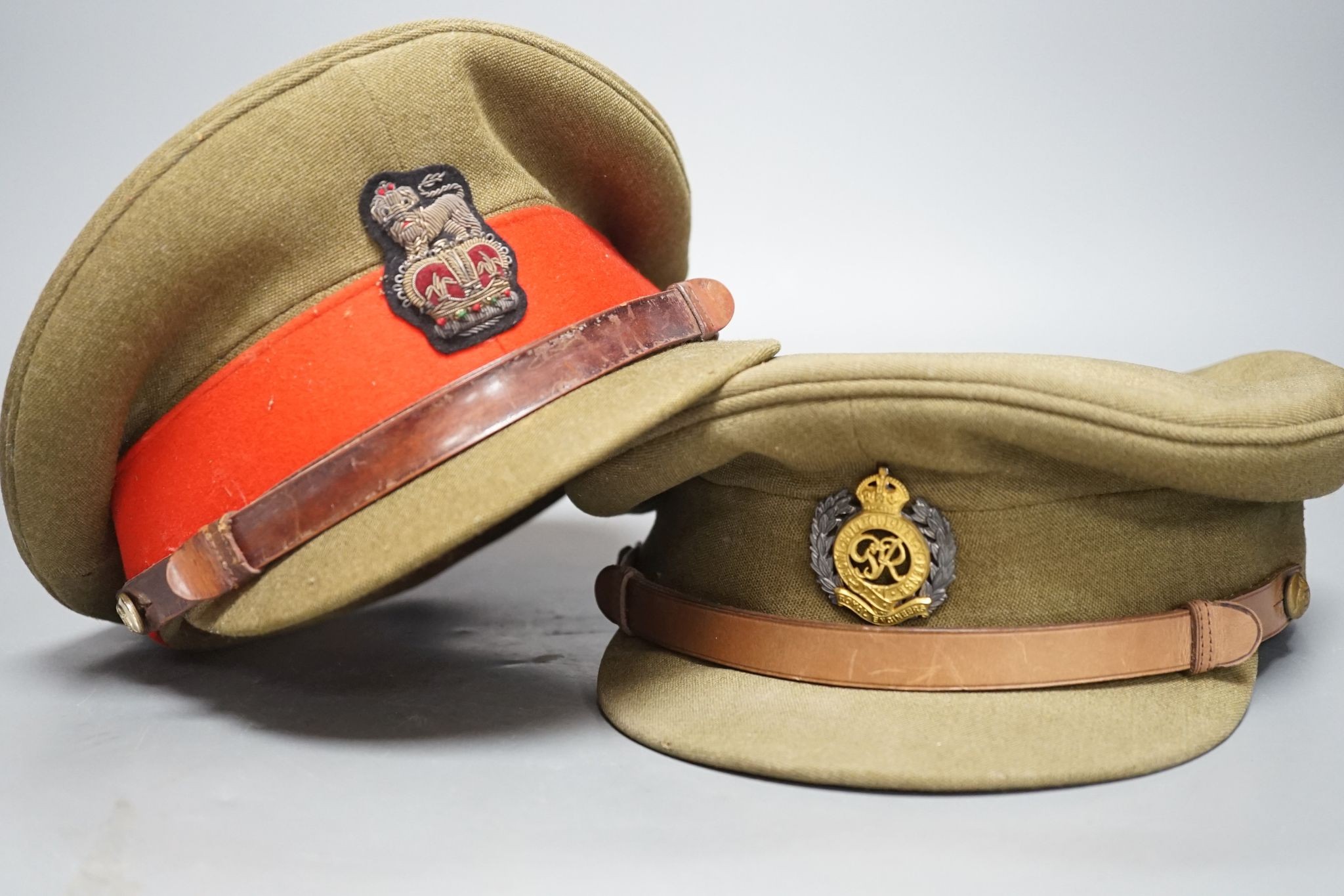 Two army officers' caps in brown leather hat box.